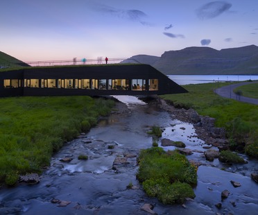 Henning Larsen signe une mairie en béton et en bois formant un pont au-dessus d’une rivière 
